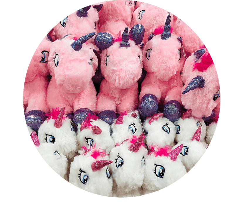 A group of stuffed unicorns sitting in front of a green background.